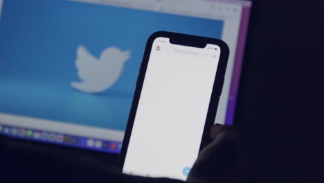 Ein-Computer--Und-Ein-Smartphone-Bildschirm-Zeigen-Das-Twitter-Logo,-Während-Eine-Fingersilhouette-Durch-Politische-Tweets-Scrollt