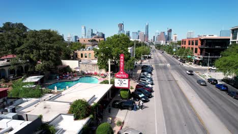 Luftdrohne,-Die-Sich-An-Einem-Sonnigen-Tag-Rückwärts-über-Touristen-Bewegt,-Die-Das-Austin-Motel-In-Texas,-USA-Betreten