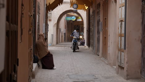 Erbaueraufnahme-Der-Straße-Von-Marrakesch-Mit-Vorbeifahrender-Frau-Und-Motorrad,-Tag