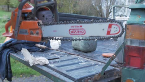 Man-picking-up-chainsaw-off-the-tailgate-of-a-pickup-truck