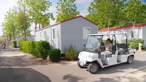 Pareja-Conduciendo-Un-Carrito-De-Golf-A-Través-De-Las-Pequeñas-Carreteras-De-Camping-En-Francia