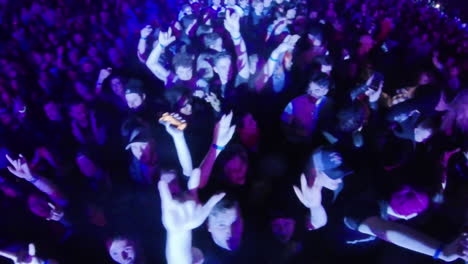 Colorful-Insta-360-Wide-Angle-View-of-Spectators-Crowd-Dancing-Cheering-During-Indoor-Music-Performance-Show-Concert,-Colorful-Spotlights-and-Audience-Celebration-With-Raised-Arms-and-Hands-Up