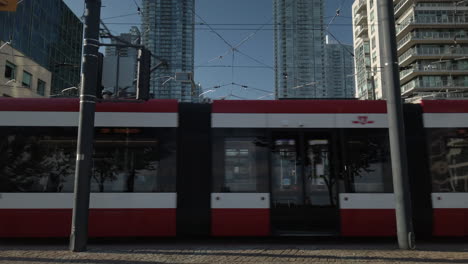 Außenaufnahme-Einer-Roten-Straßenbahn,-Die-Sich-Durch-Den-Rahmen-Bewegt,-Während-Radfahrer-Im-Vordergrund-Vorbeifahren