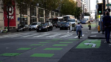 Bicicletas-Eléctricas-Cruzando-La-Calle-En-Seattle,-Washington,-Signo-De-Tienda-De-Destino-En-Segundo-Plano