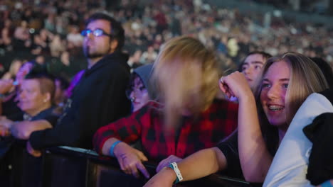 Alegre-Y-Emocionada-Mujer-Joven-Sacudiendo-La-Cabeza-Y-Largos-Cabellos-Rubios-Durante-Un-Concierto-De-Música,-Los-Espectadores-Se-Aglomeran,-La-Juventud-Y-El-Entretenimiento