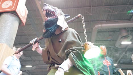 Person-dressed-up-as-rat-man-at-japan-expo-in-paris,-France,-while-tourists-walk-through-the-event