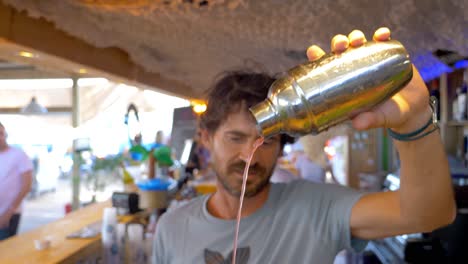 a-bartender-serving-a-cockatil-by-pouring-a-red-liquid-from-his-shaker