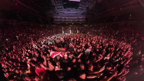 Insta-360-Weitwinkelansicht-Der-Moshpit-Szene,-Zuschauer-Drängen-Sich-Vor-Der-Bühne,-Tanzen-Jubelnd-Und-Tragen-Den-Mann-Auf-Armen-Bei-Rockmusik-Konzertshow,-Arena-Panoramablick-Mit-Bunten-Scheinwerfern