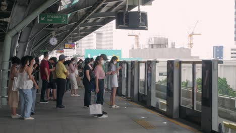 Blick-Auf-Den-Bahnsteig-Der-Bts-Skytrain-Station-Mit-Vielen-Passagieren,-Die-Auf-Den-Zug-Warten