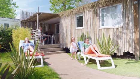 Familia-Disfrutando-De-Sus-Vacaciones-Bajo-El-Sol-Frente-A-Su-Hermoso-Bungalow