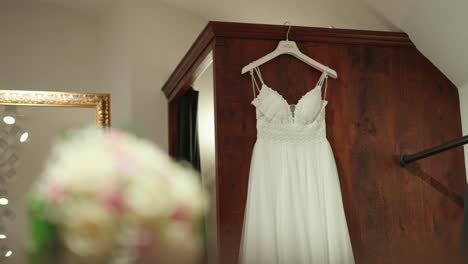 White-Wedding-Dress-Hanging-On-A-Brown-Wooden-Wall