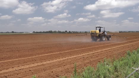 Tractor-mounted-sprayer-fertilizes-freshly-planted-crop-seeds-in-field