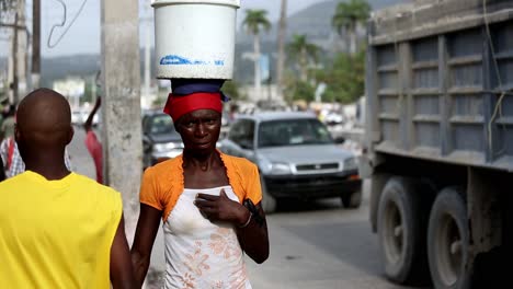 Primer-Plano-Enfocado-De-Una-Mujer-Negra-Que-Lleva-Un-Balde-En-La-Cabeza-En-La-Calle