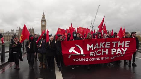 Un-Grupo-De-La-Liga-De-Jóvenes-Comunistas-De-Marzo-A-Través-Del-Puente-De-Westminster-En-El-Centro-De-Londres,-Reino-Unido