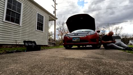 Time-Lapse-Shot-Of-Man-Fixing-His-Red-Car-In-Front-Of-His-Home,-Dog-Passing-Nearby