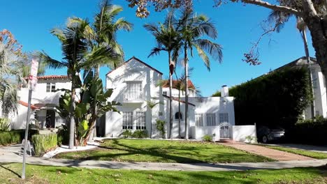 POV-Driving-Past-Upscale-Homes-In-Beverly-Hills,-Los-Angeles-On-Sunny-Clear-Day-With-Blue-Skies