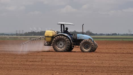 Bauer-Im-Alten-Blauen-Traktor-Sprüht-Feld-Mit-Frisch-Gepflanzten-Erntesamen