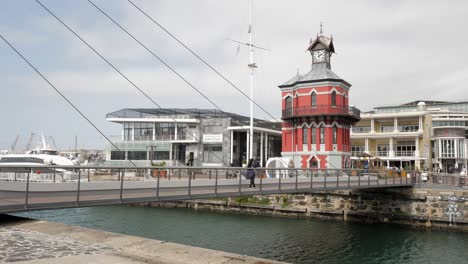 Tourist-crosses-Clocktower-Swing-Bridge-at-Alfred-Basin,-Cape-Town