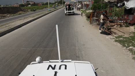 UN-transport-driving-on-street-in-Haiti,-POV-of-vehicle-on-peacekeeping-mission