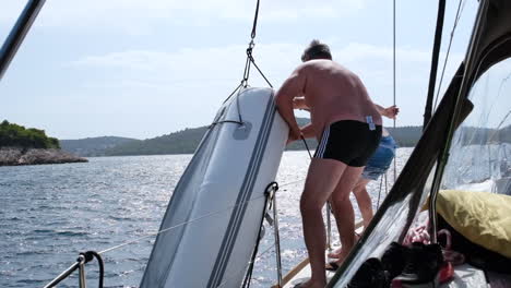 Two-men-pulling-a-dinghy-up-into-the-sailboat