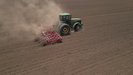 Tractor-in-field-pulls-harrow-to-loosen-topsoil-for-planting-crops