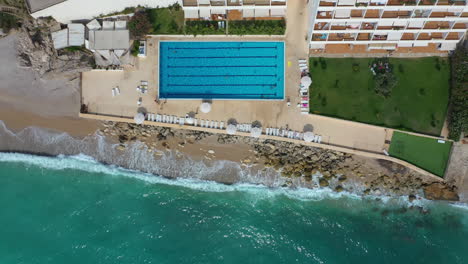 Vista-Aérea-Escénica-De-Un-Resort-De-Playa-Frente-Al-Mar-Y-Piscina-En-Byblos,-Líbano