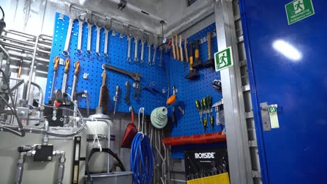 Male-ships-officer-taking-spanner-tool-from-toolboard-inside-ships-engine-room-workshop