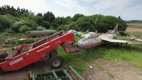 Equipo-Agrícola-Oxidado-Y-Fuselaje-Jet-Provost-De-Caza-Vista-De-órbita-Aérea-Baja-A-Través-De-Tierras-De-Cultivo-Privadas