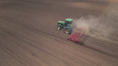 Bella-Composición-Aérea-Mientras-Un-Tractor-Agrícola-Ara-La-Tierra-Con-Una-Grada