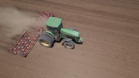 Antena:-El-Polvo-Se-Eleva-Cuando-El-Tractor-Tira-De-La-Grada-De-Resorte-A-Través-Del-Suelo-Del-Campo