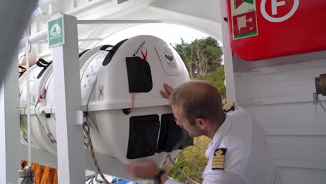 Viking-liferaft-is-routinely-inspected-by-captain-onboard-passenger-ship---Static-shot-with-blurred-railings-in-upper-foreground