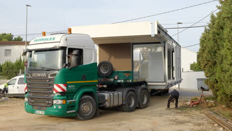 Vehículo-Pesado-De-Carga-Ancha-Que-Ingresa-Al-Sitio-De-Construcción-Que-Transporta-Una-Casa-Modular