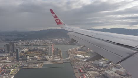 Vista-Desde-El-Interior-De-La-Cabina-Del-Avión-Neo-Airasia-A320-Mientras-Volaba-Sobre-La-Ciudad-De-Fukuoka-Hakata-A-Través-De-La-Ventana-Con-Vista-Al-Ala