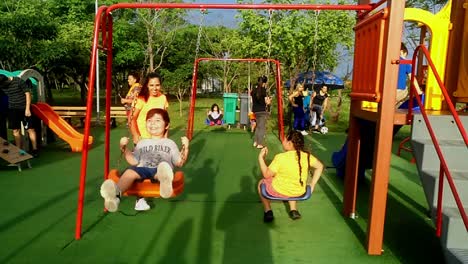 Madre-Balanceando-A-Su-Pequeño-Y-Lindo-Hijo-En-Un-Parque-Público-En-El-Patio-De-Recreo,-Asunción,-Paraguay