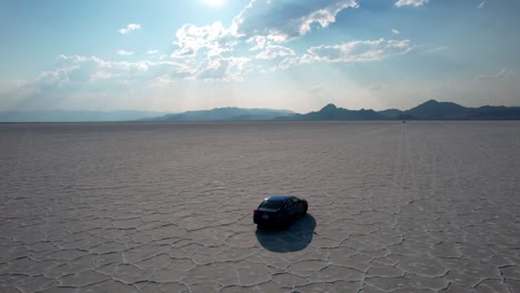 Aerial-drone-following-shot-of-a-car-driving-at-empty-Bonneville-Salt-Flats