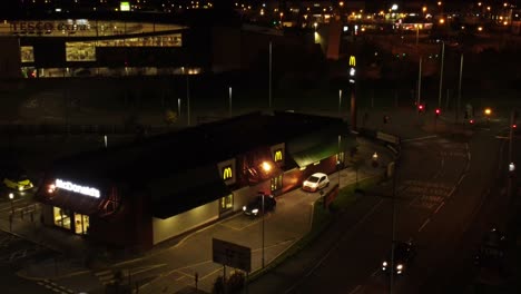 Cola-De-Coches-Fuera-De-La-Comida-Rápida-De-Mcdonalds-En-Coche-Por-La-Noche-En-La-Ciudad-Del-Norte-Del-Reino-Unido-Vista-Aérea-De-Alejamiento