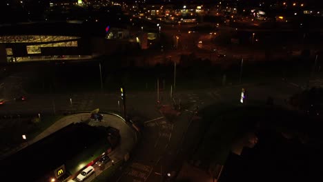 Vuelo-Nocturno-En-órbita-Por-La-Autopista-De-La-Ciudad-Del-Reino-Unido-Con-Luces-De-Calle-Iluminadas-Y-Vista-Aérea-Del-Logotipo-Publicitario-De-McDonald&#39;s