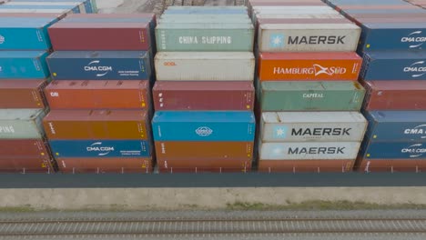 Aerial-view-of-many-empty-metal,-rusted,-and-colored-sea-containers-lined-up-in-a-port-terminal