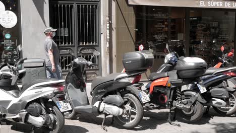 Toma-Panorámica-De-Muchas-Motocicletas-Estacionadas-A-Lo-Largo-Del-Espacio-De-Estacionamiento-A-Lo-Largo-De-La-Calle-Al-Lado-De-La-Acera