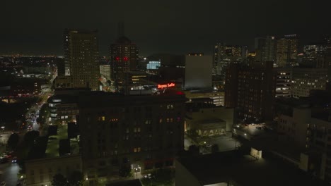 Vista-Aérea-Hacia-El-Cartel-De-Bayou-Lofts-En-La-Parte-Superior-Del-Edificio,-Noche-En-Houston,-Ee.uu.---Dando-Vueltas,-Disparo-De-Drones