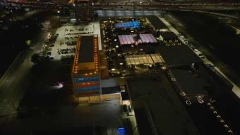 Aerial-view-around-the-skylawn-park-on-top-of-the-illuminated-POST-Houston-Cultural-center,-night-in-Texas,-USA---orbit,-drone-shot