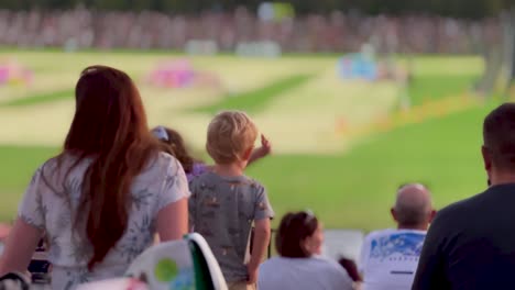 Close-up-behind-a-family-cheering-at-a-show-at-an-outdoor-stadium-event