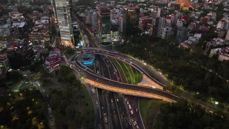 Vista-Aérea-Frente-Al-Tráfico-En-La-Fuente-De-Petroleos,-Rotonda-Y-Cruce,-Atardecer-En-La-Ciudad-De-México---Ascendente,-Disparo-De-Drones