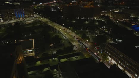 Tram-driving-over-the-Main-Street-Viaduct-in-Houston-city,-evening-in-Texas,-USA---Aerial-view