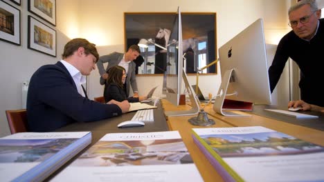 Toma-Panorámica-Que-Muestra-A-Un-Hombre-De-Negocios-Y-Una-Mujer-De-Negocios-Trabajando-En-La-Oficina-Del-Arquitecto-Con-Una-Computadora-Apple---Cámara-Lenta