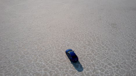 Aerial-shot-of-car-driving-in-empty-Bonneville-Salt-Flats,-quick-escape-vacation