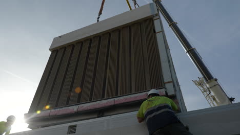 Low-angle-contractors-preparing-modular-home-unit-removing-from-construction-site-truck