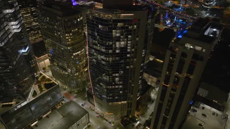 Aerial-view-in-front-of-the-Hines,-Brava-apartment-building-in-Houston-city,-night-in-Texas,-USA---descending,-drone-shot