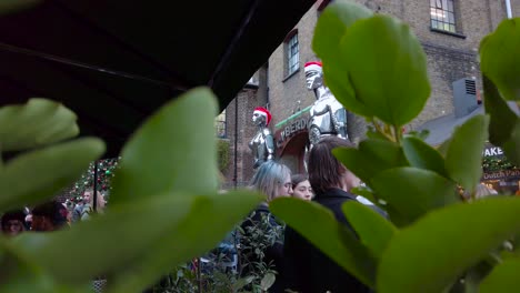 Foto-De-Enormes-Robots-Frente-A-Un-Perro-Cibernético,-Londres-Con-Lugareños-Disfrutando-De-Bocadillos-Al-Aire-Libre-Durante-El-Día