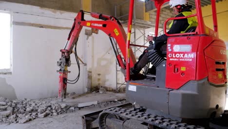 Person-using-his-excavator-for-drilling-the-floor-in-an-indoor-construction-site